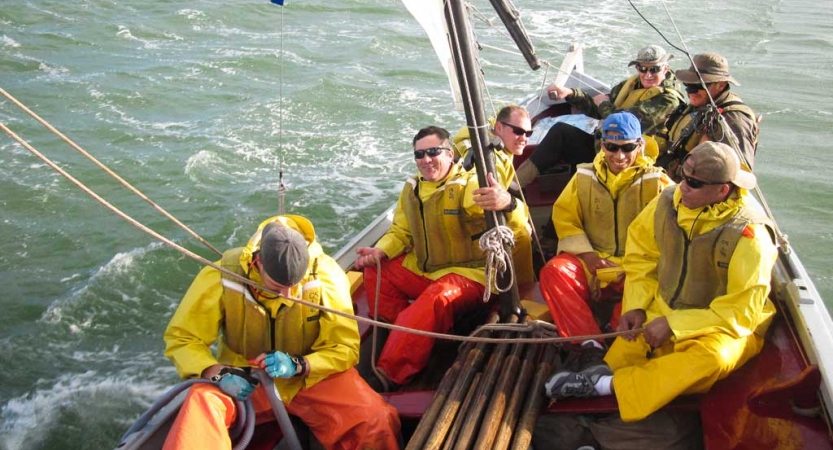 a group of veterans navigate a sailboat on an outward bound expedition